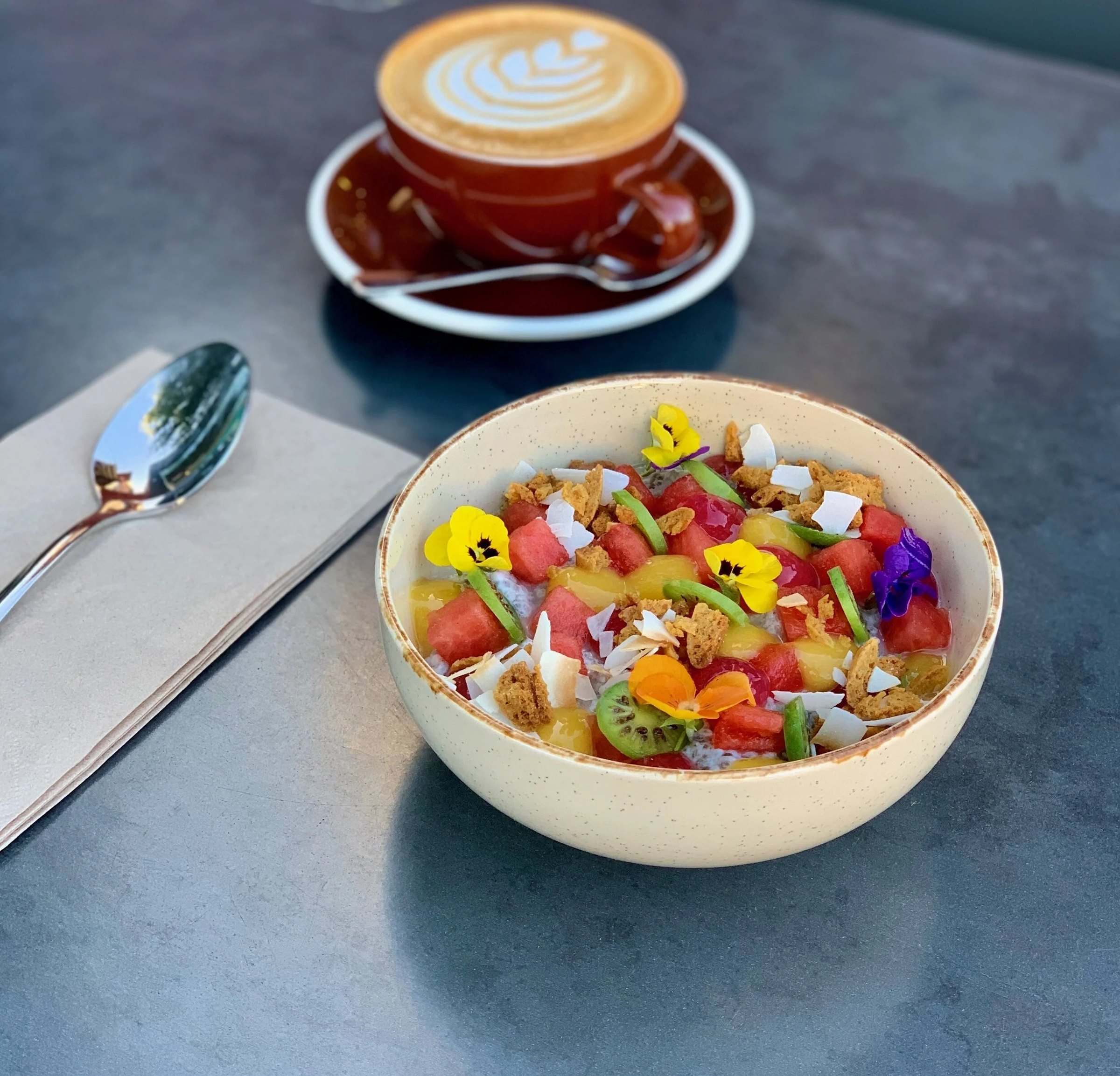 A latte and a colourful breakfast bowl on one of our tables