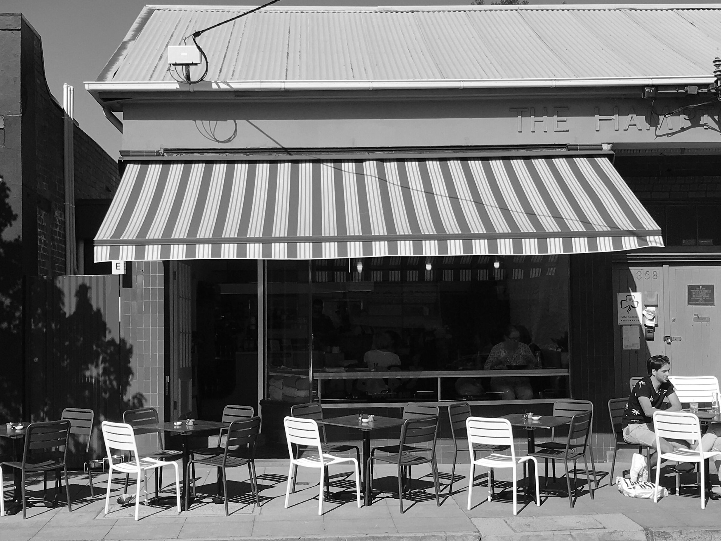 The Paperboy shopfront on Hampton Street, with its striped awning and tables